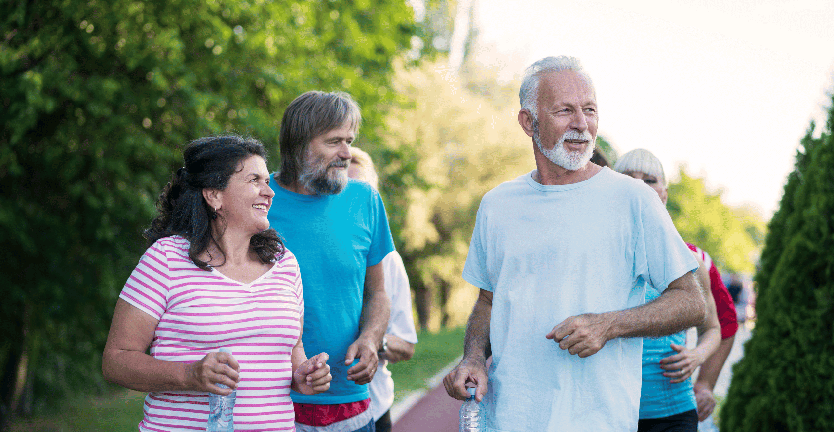 A group of older adults smiling while on a jogging path.