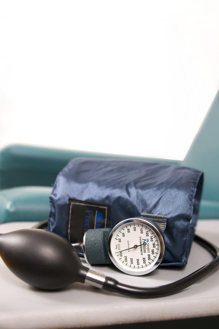 Manual blood pressure cuff on a table with armrest in the background.