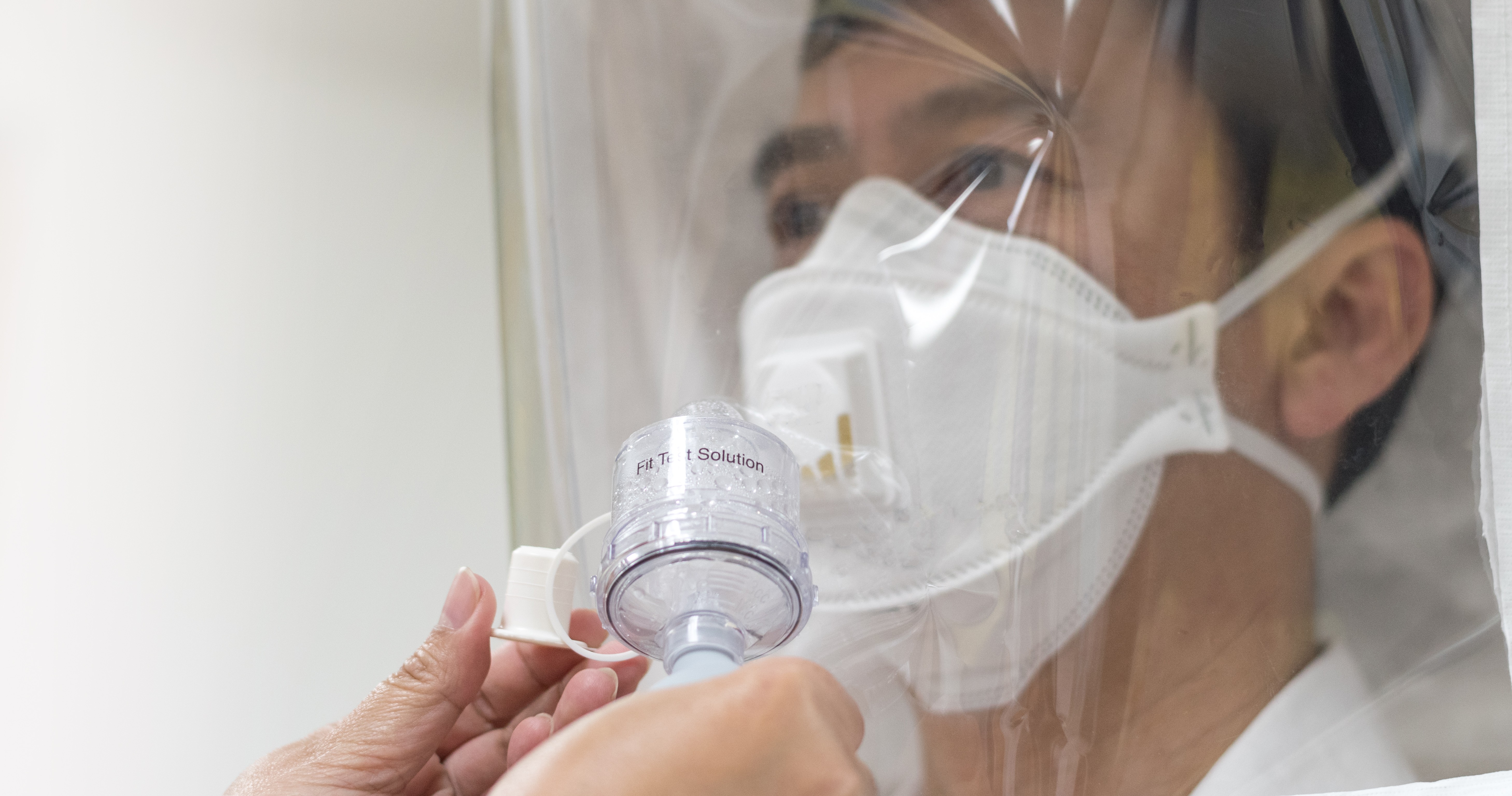 A health care provider participates in a fit test of his N95 mask wearing a hood.
