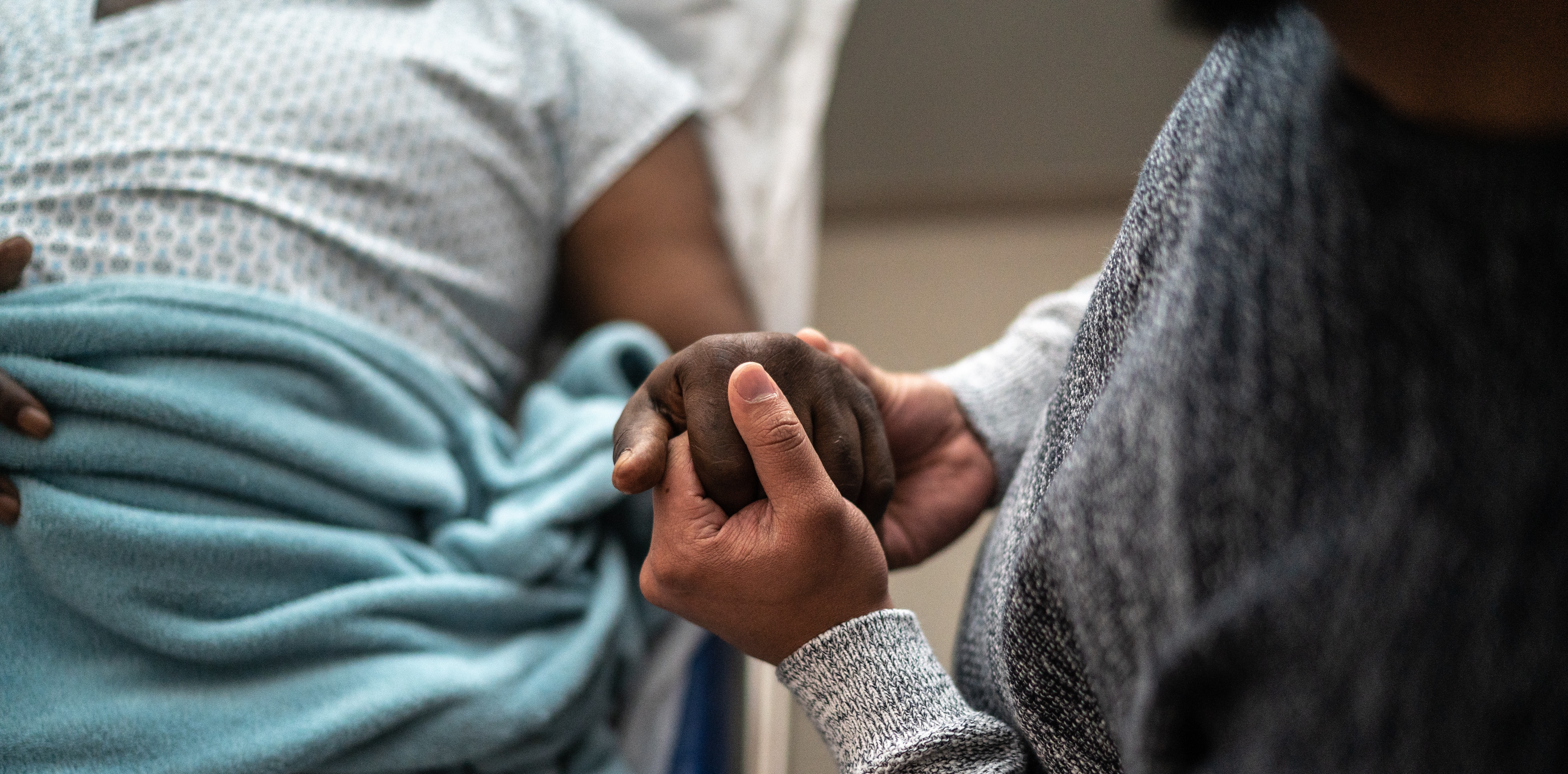 Mother holding son's hand in hospital bed