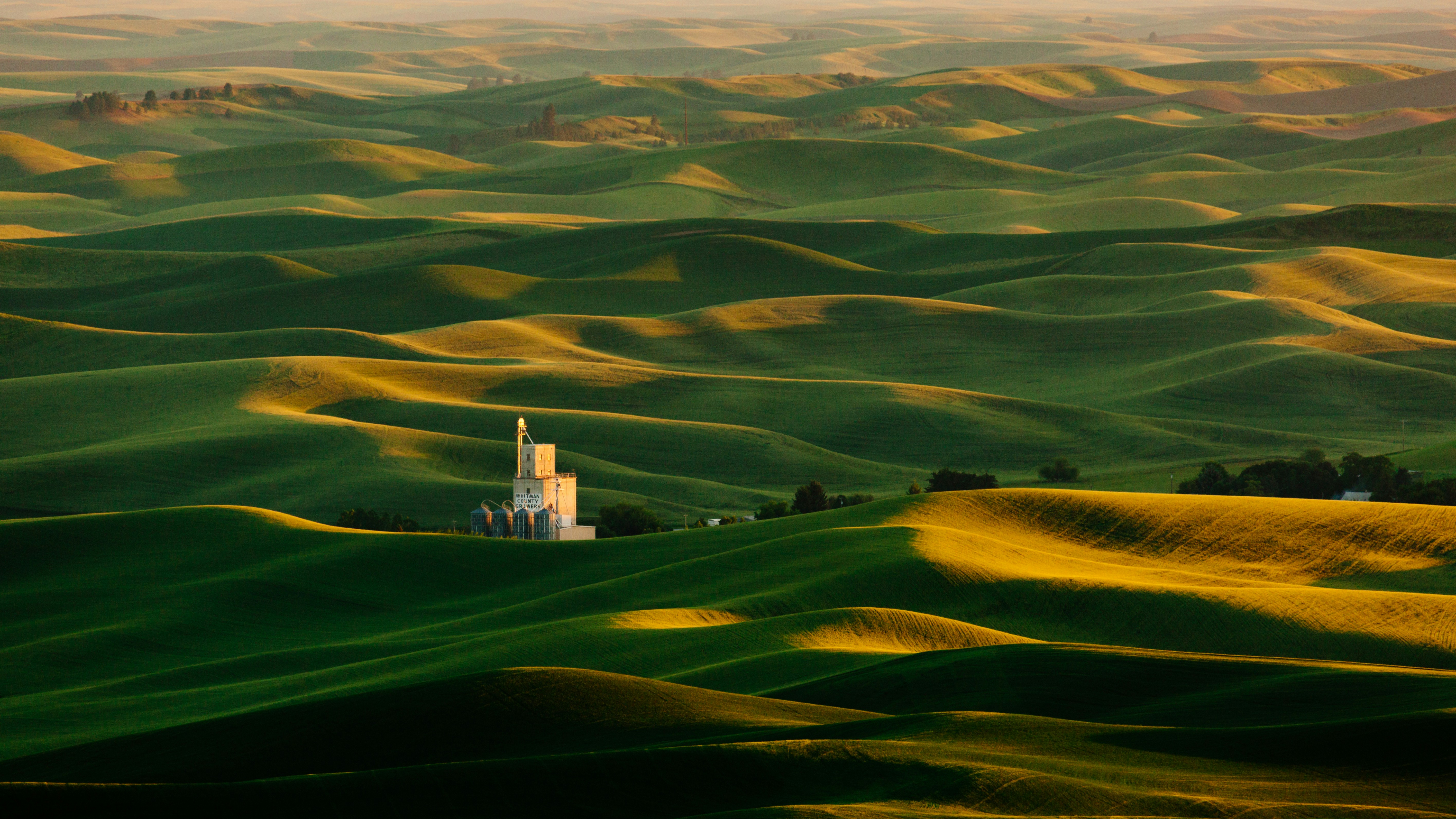 Rolling hills at sunset in the Palouse with a far-off building