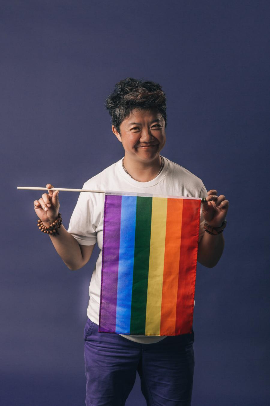 smiling person holding a pride flag