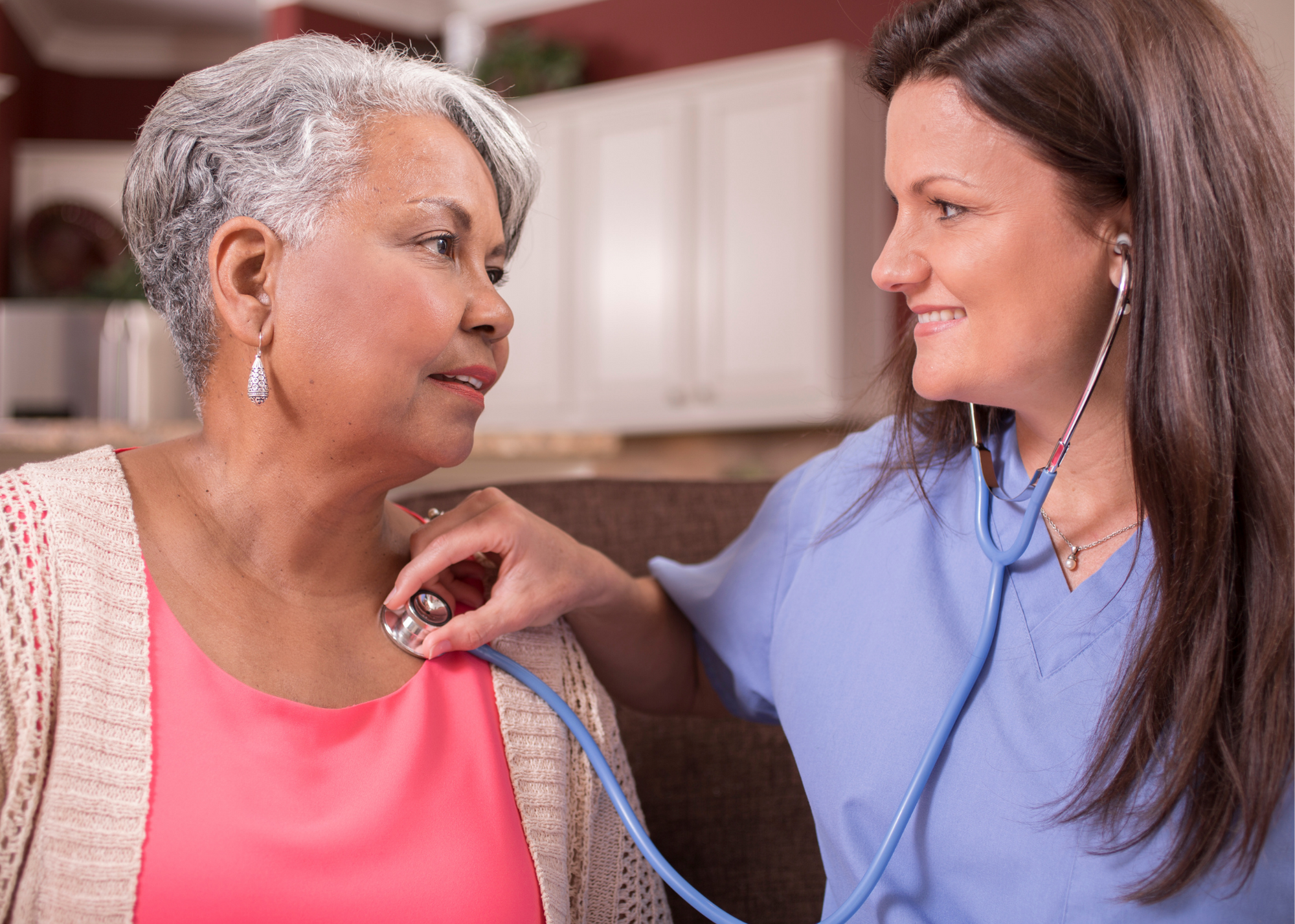 Stock photo of a smiling female health care provider uses a stethescope on a smiling elderly woman