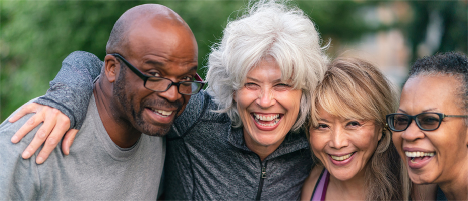 A diverse group of four smiling middle-aged people in exercise clothing