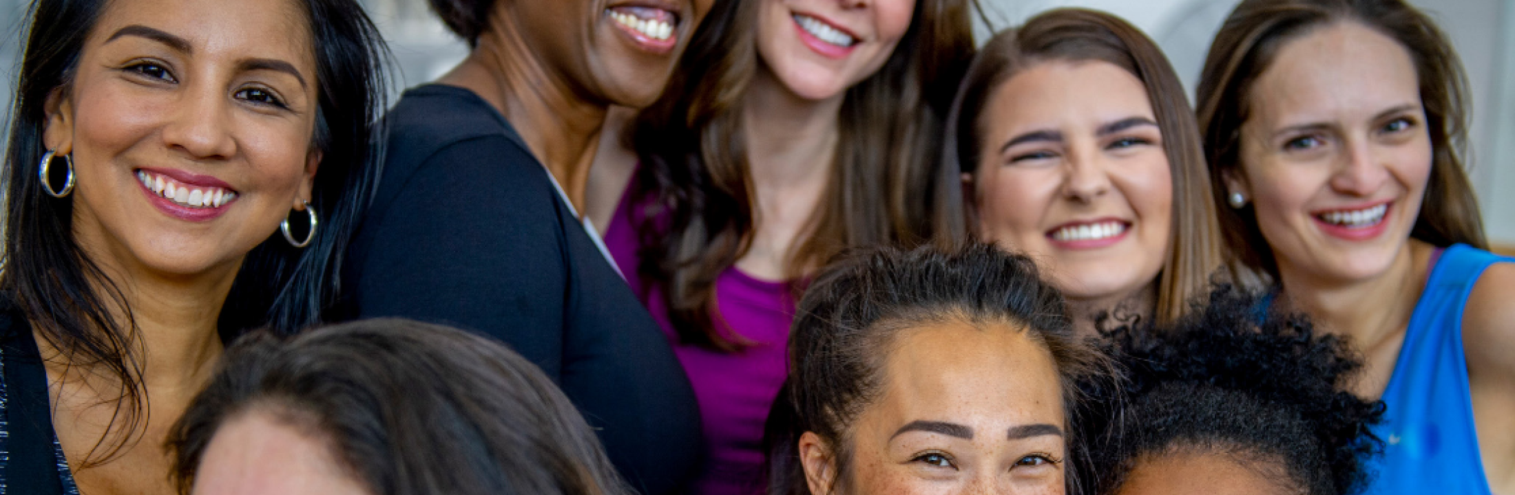Close of a group of women smiling as they stand close together.