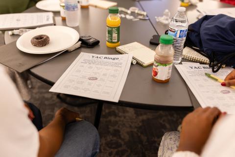 YAC meeting materials on a table, including snacks, a getting to know you bingo activity, drinks, and backpacks.