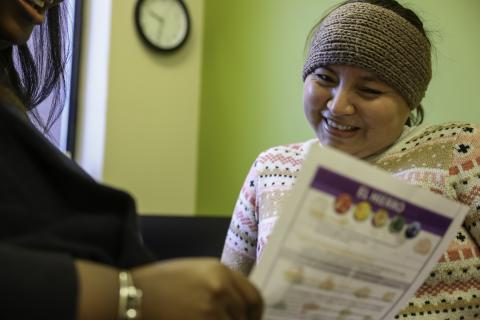 WIC staff shows a printed resource to a parent in a WIC clinic.
