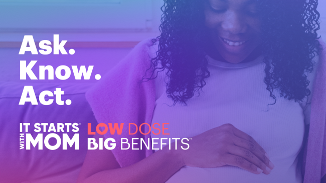 A pregnant women with dark skin looking down. 