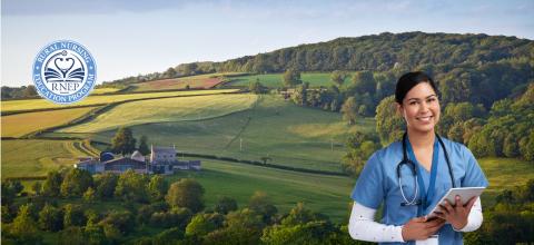 Young female nurse in blue scrubs wearing stethoscope smiles holding tablet in front of vast rural background showing a home and green fields.