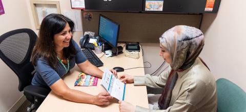 WIC staff shows a printed resource in Arabic to a participant.